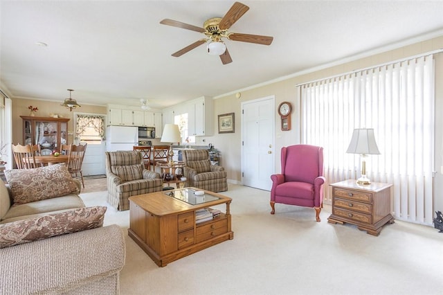 living area with light colored carpet, a ceiling fan, and crown molding