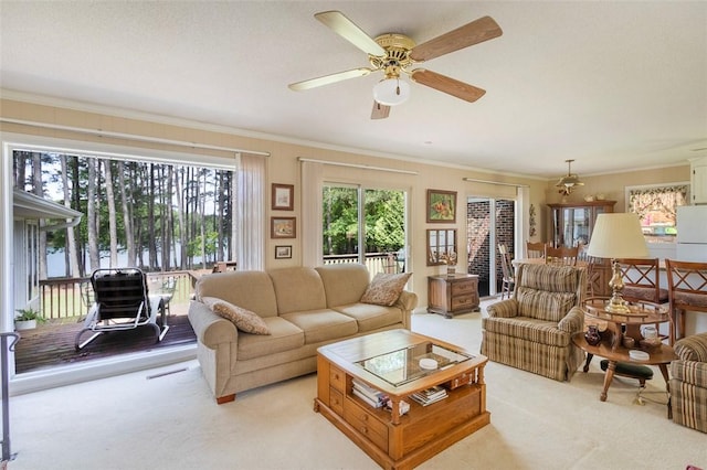 living room with ornamental molding, a ceiling fan, and light colored carpet