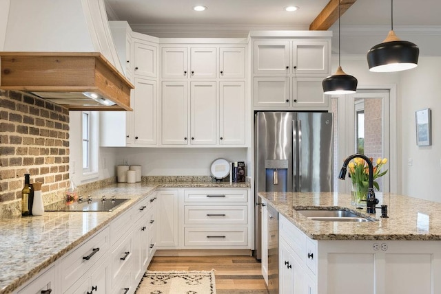 kitchen with white cabinetry, a sink, light wood-style floors, black electric cooktop, and a center island with sink