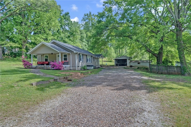 view of front of house featuring a porch, fence, driveway, a detached carport, and a front yard