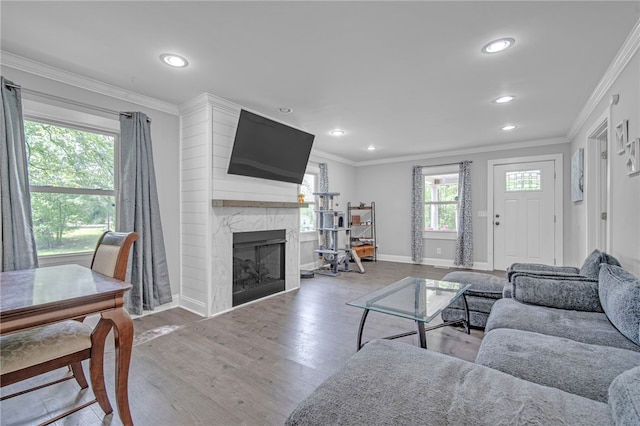 living area featuring recessed lighting, a fireplace, baseboards, ornamental molding, and wood finished floors