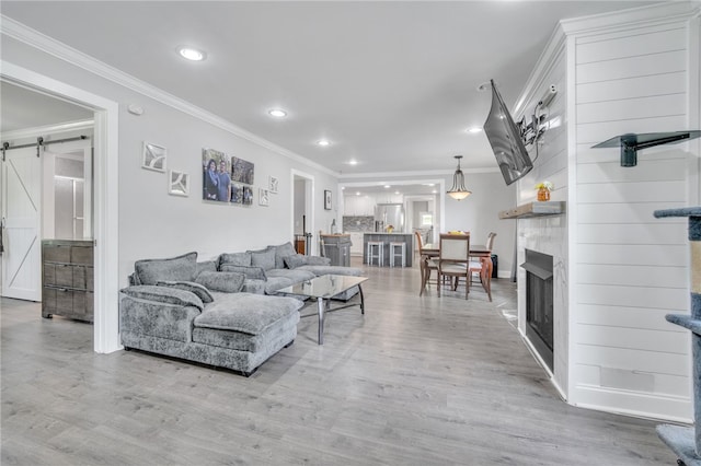 living area with a barn door, crown molding, and recessed lighting