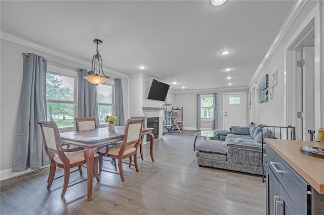 dining space with light wood-style flooring, baseboards, recessed lighting, ornamental molding, and a premium fireplace