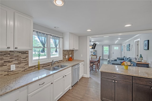 kitchen with stainless steel dishwasher, light wood finished floors, a sink, and white cabinets