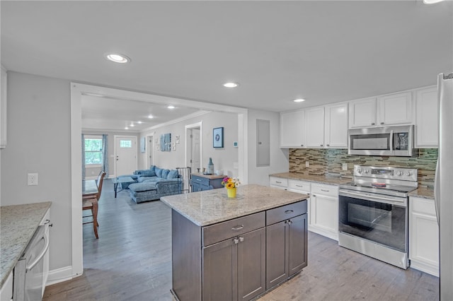 kitchen featuring light wood finished floors, open floor plan, white cabinetry, and stainless steel appliances