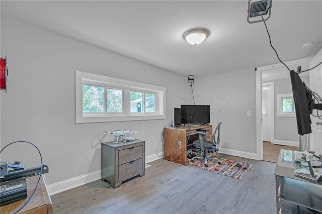 office space with plenty of natural light, visible vents, wood finished floors, and baseboards