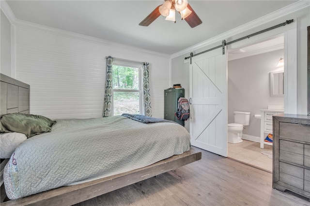 bedroom featuring wood finished floors, a barn door, ceiling fan, baseboards, and crown molding