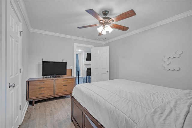bedroom with a fireplace, light wood finished floors, baseboards, a ceiling fan, and crown molding