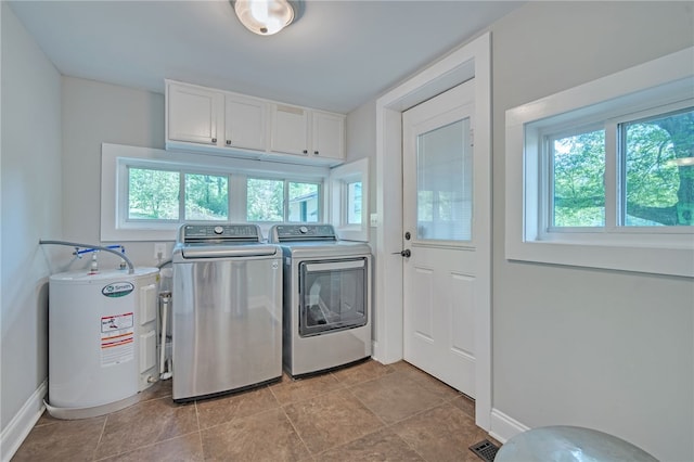 clothes washing area with water heater, cabinet space, washing machine and clothes dryer, and plenty of natural light