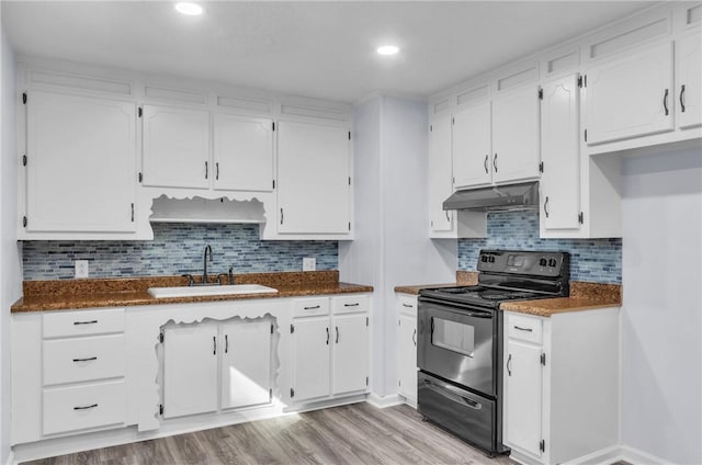 kitchen featuring white cabinetry, a sink, dark countertops, under cabinet range hood, and electric range