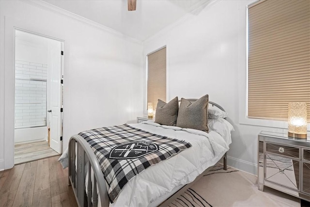 bedroom with connected bathroom, crown molding, baseboards, wood finished floors, and a ceiling fan