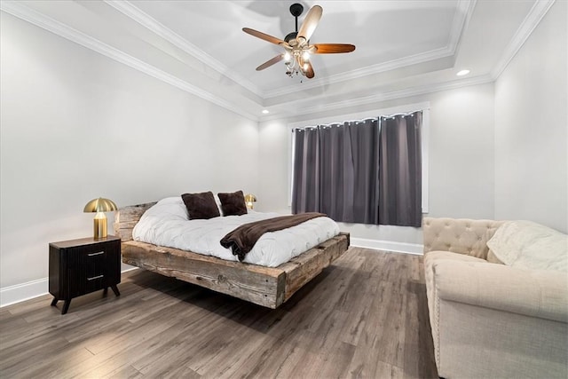 bedroom featuring crown molding, a raised ceiling, ceiling fan, baseboards, and wood finished floors