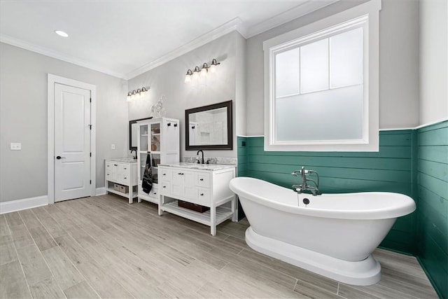 full bath featuring vanity, crown molding, a wainscoted wall, a soaking tub, and wood finished floors