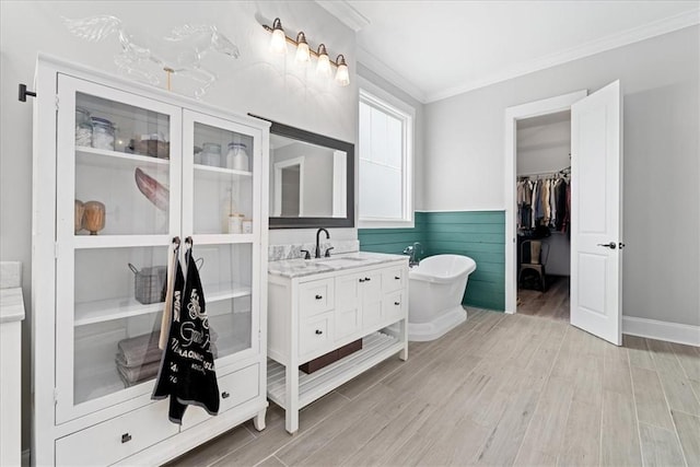 full bath featuring a soaking tub, a wainscoted wall, ornamental molding, wood finished floors, and vanity