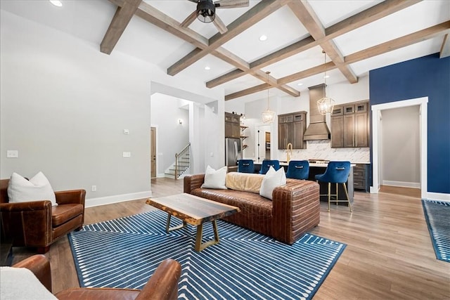 living room featuring beam ceiling, baseboards, coffered ceiling, and stairway