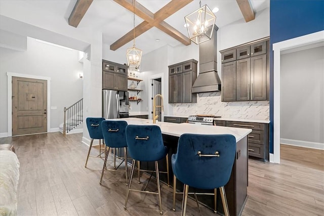kitchen with light wood-style flooring, a chandelier, freestanding refrigerator, beam ceiling, and backsplash