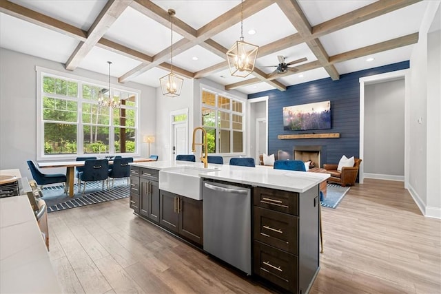 kitchen featuring light wood finished floors, a sink, coffered ceiling, baseboards, and stainless steel dishwasher