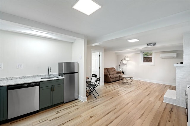 kitchen featuring a wall mounted air conditioner, a sink, appliances with stainless steel finishes, and light wood-style floors