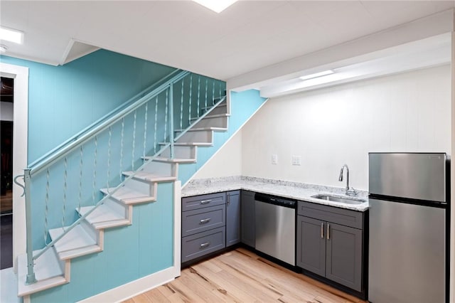 bar featuring a sink, stairway, appliances with stainless steel finishes, and light wood-style floors