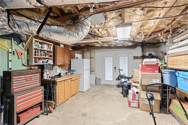 unfinished below grade area with a workshop area and freestanding refrigerator