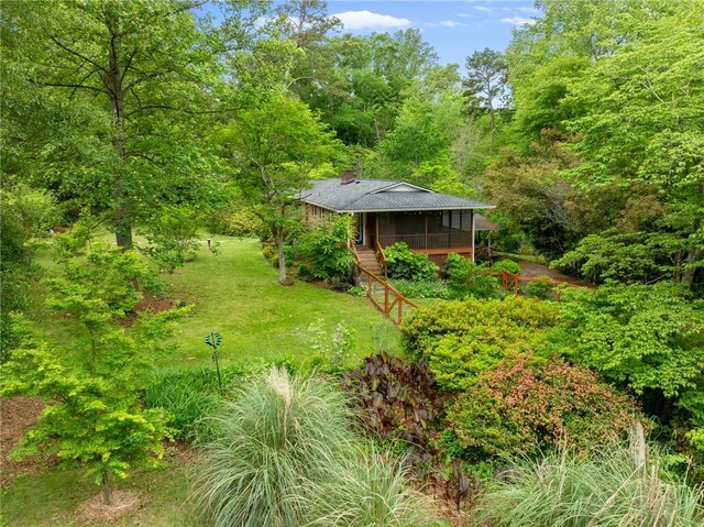 view of yard with a wooden deck and a view of trees