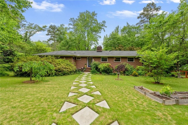 view of front of home featuring a front lawn, a vegetable garden, brick siding, and a chimney