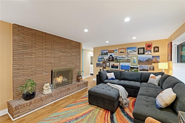 living room with baseboards, recessed lighting, wood finished floors, and a brick fireplace