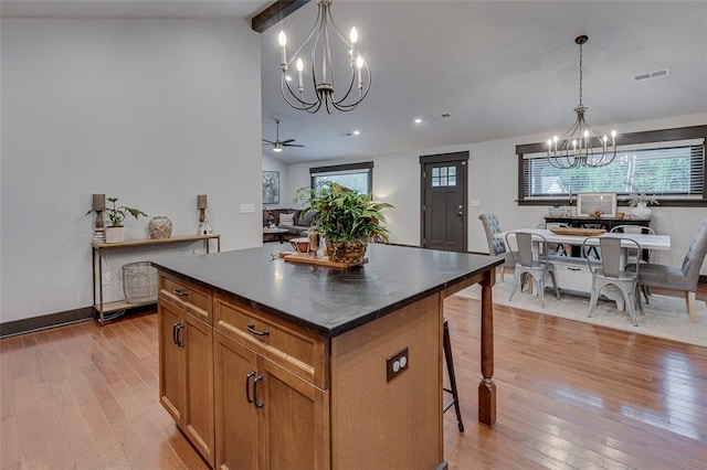 kitchen featuring brown cabinets, dark countertops, light wood-style floors, lofted ceiling with beams, and a center island