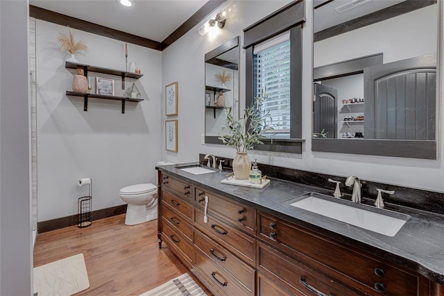 full bathroom with toilet, a sink, wood finished floors, and baseboards