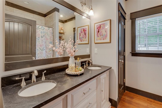 full bathroom with double vanity, wood finished floors, a shower with shower curtain, and a sink