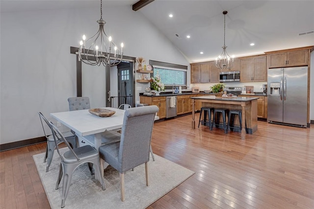 dining room with an inviting chandelier, beam ceiling, high vaulted ceiling, and light wood-style flooring