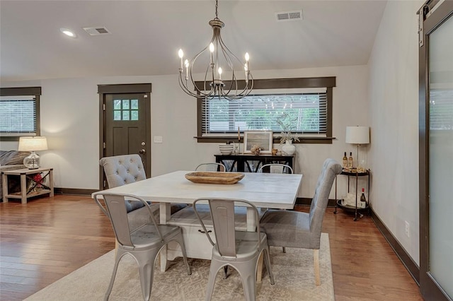 dining room featuring visible vents, a chandelier, wood finished floors, and baseboards