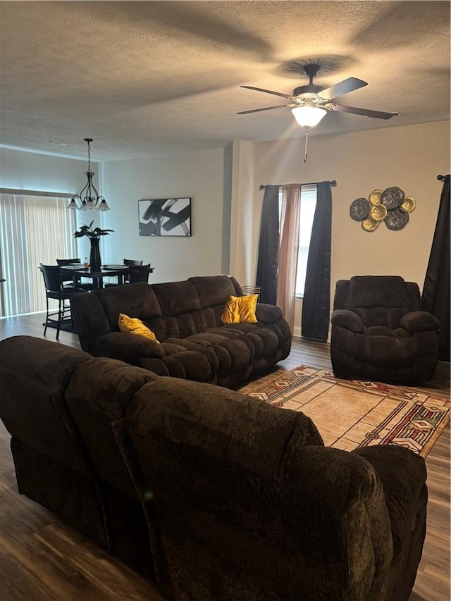 living area with a wealth of natural light, ceiling fan, a textured ceiling, and dark wood-type flooring