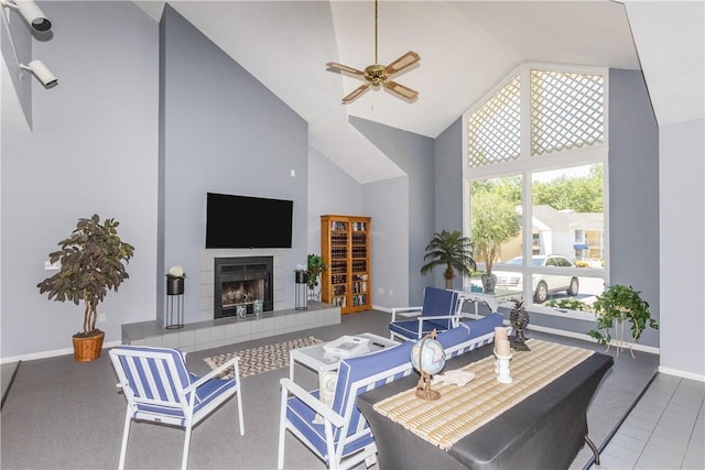 living room with carpet flooring, a tiled fireplace, high vaulted ceiling, ceiling fan, and baseboards