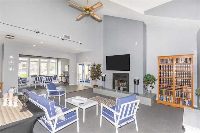 living room featuring a ceiling fan, visible vents, high vaulted ceiling, and a fireplace