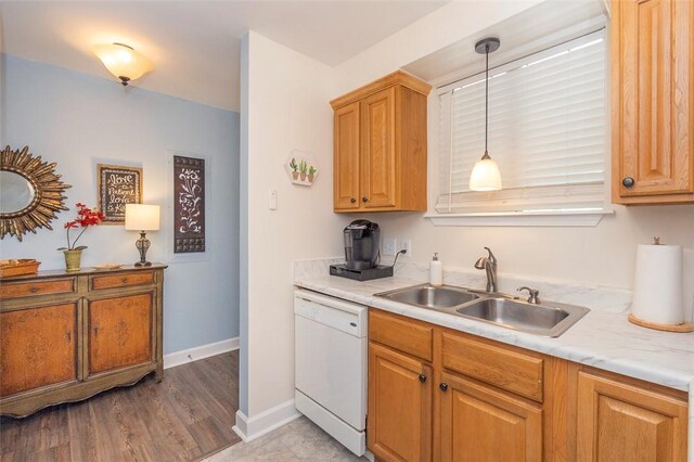 kitchen with light countertops, white dishwasher, a sink, baseboards, and pendant lighting