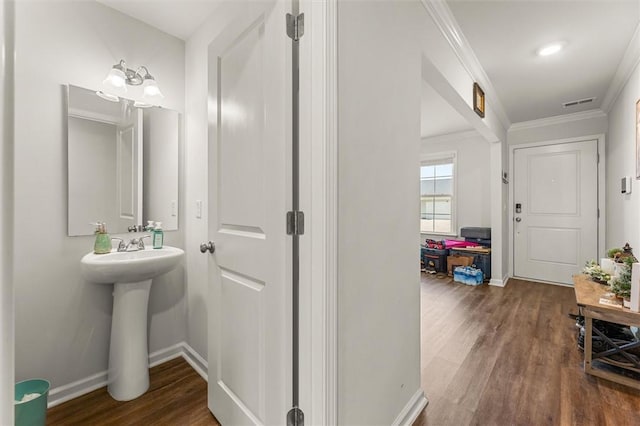 interior space with ornamental molding, visible vents, wood finished floors, and baseboards