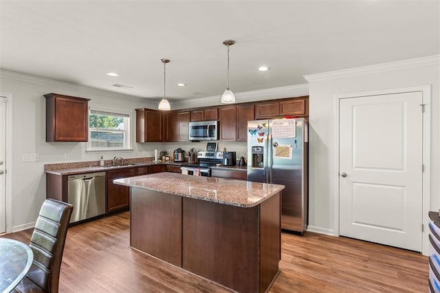 kitchen with crown molding, a sink, wood finished floors, and stainless steel appliances