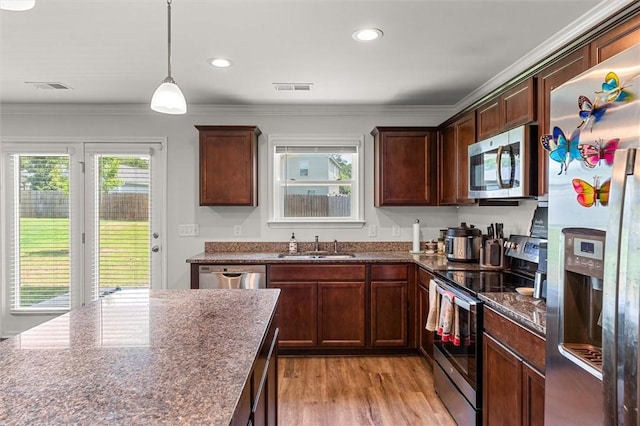 kitchen featuring dark stone counters, a sink, light wood-type flooring, visible vents, and appliances with stainless steel finishes