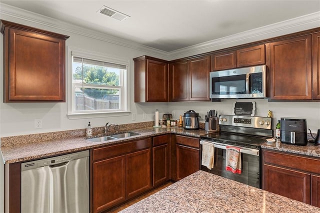 kitchen featuring a sink, crown molding, stone counters, visible vents, and appliances with stainless steel finishes