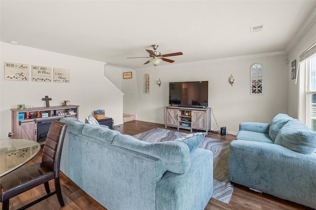 living area featuring ceiling fan, visible vents, baseboards, ornamental molding, and wood finished floors