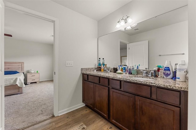 ensuite bathroom featuring baseboards, double vanity, ensuite bathroom, and a sink
