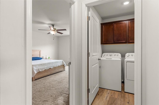 clothes washing area with a ceiling fan, cabinet space, light wood-style flooring, and washer and clothes dryer
