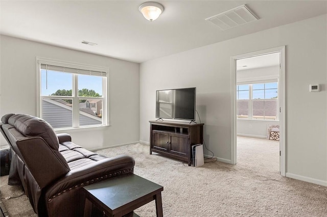 carpeted living area with baseboards, visible vents, and a wealth of natural light