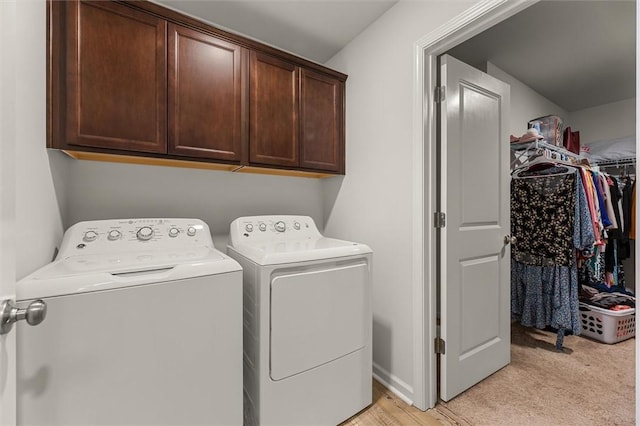 clothes washing area featuring separate washer and dryer, cabinet space, light carpet, and baseboards