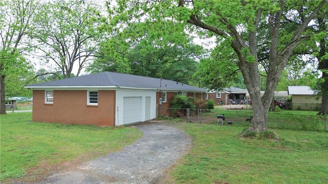 exterior space with fence, a front yard, aphalt driveway, and an attached garage