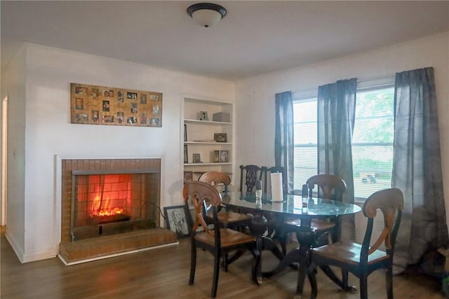 dining space featuring built in shelves, wood finished floors, and a warm lit fireplace