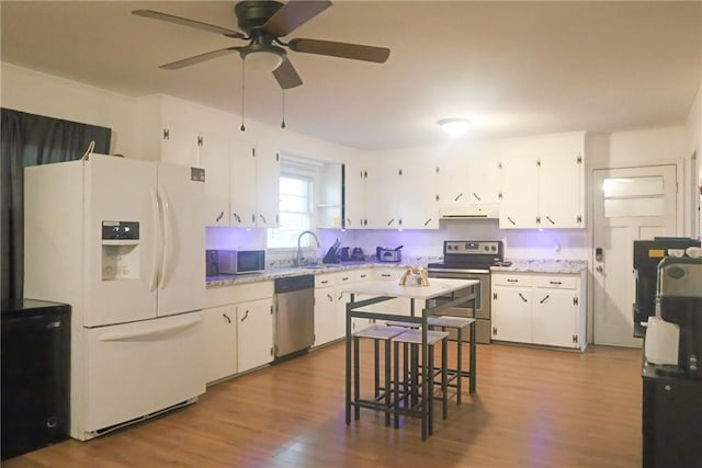 kitchen with white cabinetry, appliances with stainless steel finishes, under cabinet range hood, wood finished floors, and a ceiling fan