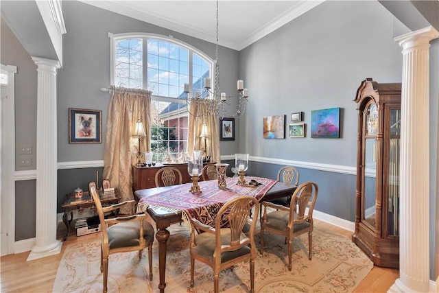 dining area featuring baseboards, light wood-style flooring, and ornate columns