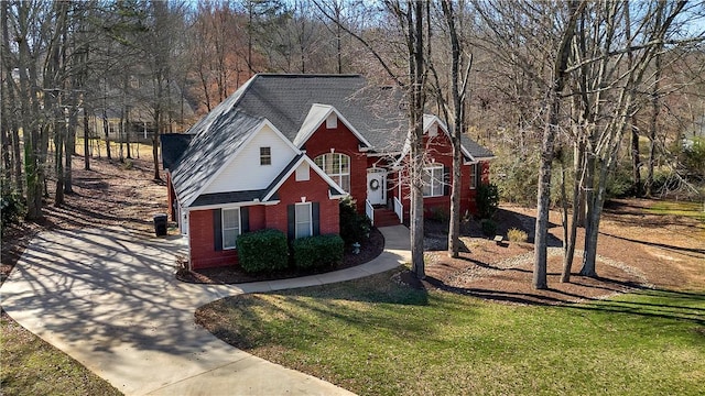 traditional-style house with a front lawn, a shingled roof, and brick siding